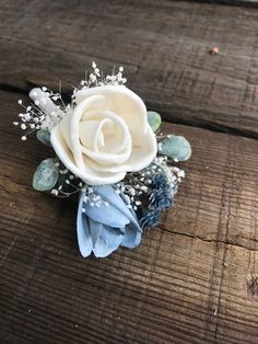 a white rose and baby's breath boutonniere on a wooden table