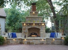 an outdoor fireplace with blue and white pillows