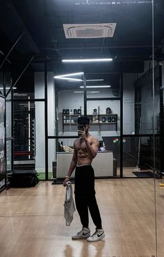 a shirtless man taking a selfie with his cell phone in an empty room