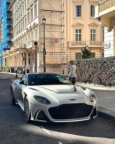 a man standing next to a silver sports car in the middle of an empty street