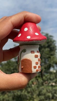 a hand is holding a tiny mushroom house