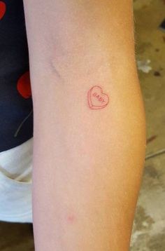 a small red heart tattoo on the arm