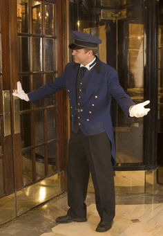 a man in a blue suit and hat is holding his hands out