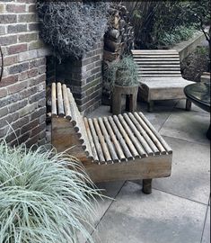 a wooden bench sitting next to a brick wall and potted plants on top of it