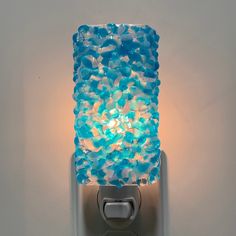 a light that is on the side of a wall with some glass beads in it