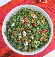 a white bowl filled with greens and pomegranates