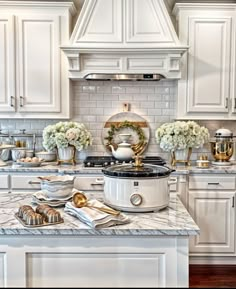 a kitchen with white cabinets and marble counter tops, gold trimmings on the stove