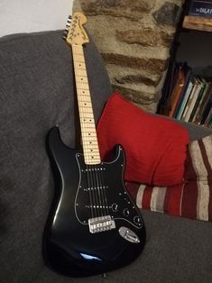 a black guitar sitting on top of a couch