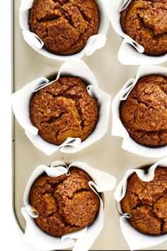 six muffins in white paper lined up on a baking tray