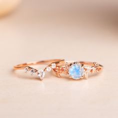 two gold rings with opal and diamond accents on top of a white countertop