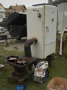 an old stove sitting on top of a grass covered field next to a pile of junk