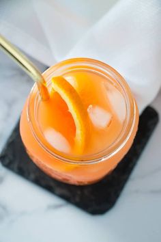 an orange drink in a glass with a gold spoon