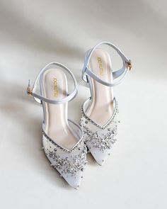 a pair of white high heeled shoes with crystal embellishments