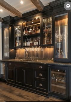 an elegant bar with black cabinets and glass doors is featured in this kitchen remodel