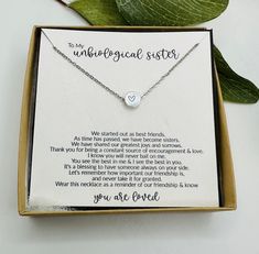 a box with a necklace in it on top of a table next to some leaves