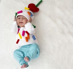 a baby laying on its back wearing a white hat and blue pants with lots of magnets attached to it's head