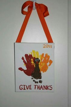 a handprinted sign hanging on the wall with a ribbon around it that says give thanks