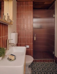 a bathroom with a sink, toilet and shower stall in the background is tiled flooring