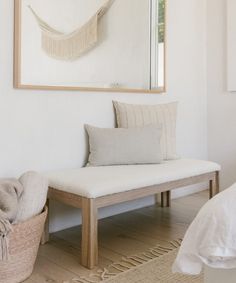 a white bench sitting in front of a mirror on the wall next to a bed