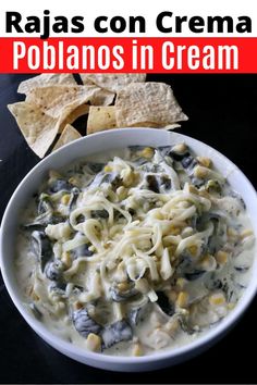 a white bowl filled with pasta and cheese next to tortilla chips on a black surface