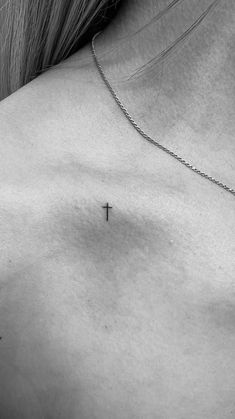 a cross tattoo on the back of a woman's shoulder is shown in black and white