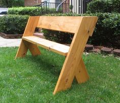 a wooden bench sitting on top of a green grass covered park area next to a building