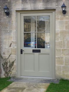 the front door to a building with two lights on each side and a car parked in the window