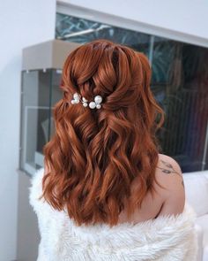 a woman with long red hair and white flowers in her hair is shown from the back