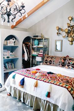 a room with a bed, bookshelf and various items on the shelves in it