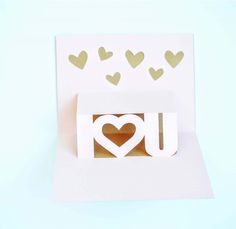 a white card with hearts and the word i love you cut out of paper on it