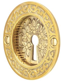 an ornate gold door knob with a keyhole and floral design on the front, isolated against a white background