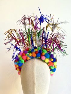 The Firework headpiece will go off with a BANG! Celebrate the New Year with this sparkling head carnival.  This colourful beauty is lovingly handmade with Pompoms and embellishments  on satin headband. The fire headpiece would be ideal for Bonfire night,  New Years Eve or a big birthday celebration. How about matching headpieces for your dinner guests  This delicate headpiece is fragile. Take care of it and it will last for many festivities.  The Bau House headpieces are handmade and unique, just like the fabulous ones that wear them. Each Firework headpiece will vary slightly in colour as they are handmade and not identical.  One size.  Not suitable for toddlers and babies.  KEEP AWAY FROM FIRE Colours may run if they get wet.  There are no returns or exchanges on this item. Fireworks Costume, Firework Costume, Fire Headpiece, New Years Eve Headband, Firework Party, Rainbow Hat, Diy Carnival, Festival Headpiece, Colorful Headbands