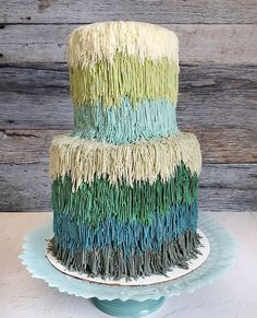 a three tiered cake decorated with multi - colored fringes on a blue plate