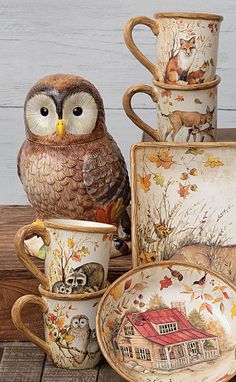 an owl figurine sitting on top of a stack of coffee cups and saucers