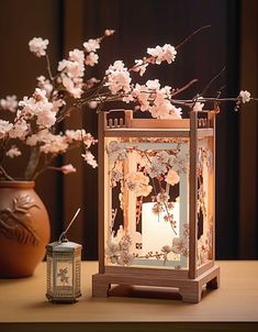 a vase with flowers and a lit candle on a table next to a decorative lantern