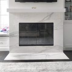 a tv mounted on the wall above a fireplace in a living room with white walls