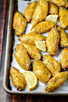 chicken wings with lemon slices on a baking sheet