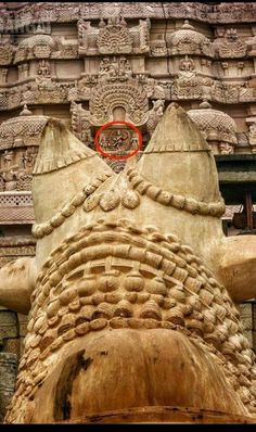 an intricately carved stone sculpture in front of a building with carvings on the walls