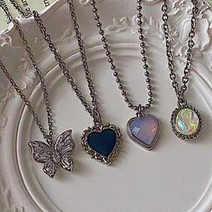 four necklaces on a white plate with a butterfly and heart pendant in the middle