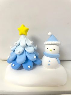 a small snowman next to a blue and white christmas tree with a star on top