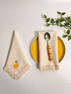 a yellow plate with a spoon and fork on it next to a napkin that has an orange design