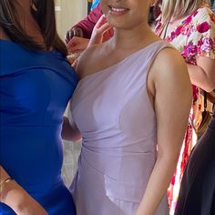 two women standing next to each other at a formal event, one in a blue dress and the other in a pink gown