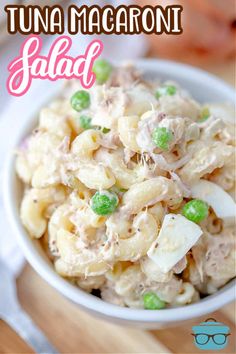 a bowl filled with macaroni salad on top of a wooden table next to a fork