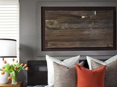 a bedroom with gray and orange colors in the bedding, pillows, and decor