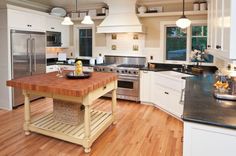 a large kitchen with an island in the center and stainless steel appliances on both sides