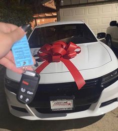 a person holding a car key with a red bow on it's tailgate