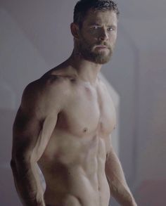 a shirtless man standing in front of a mirror looking at the camera with his hands on his hips