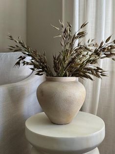 a white vase with some plants in it