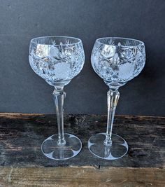 two clear goblets sitting on top of a wooden table next to each other