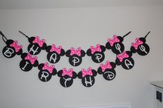 minnie mouse birthday banner with pink and black bows on it, hanging from the wall